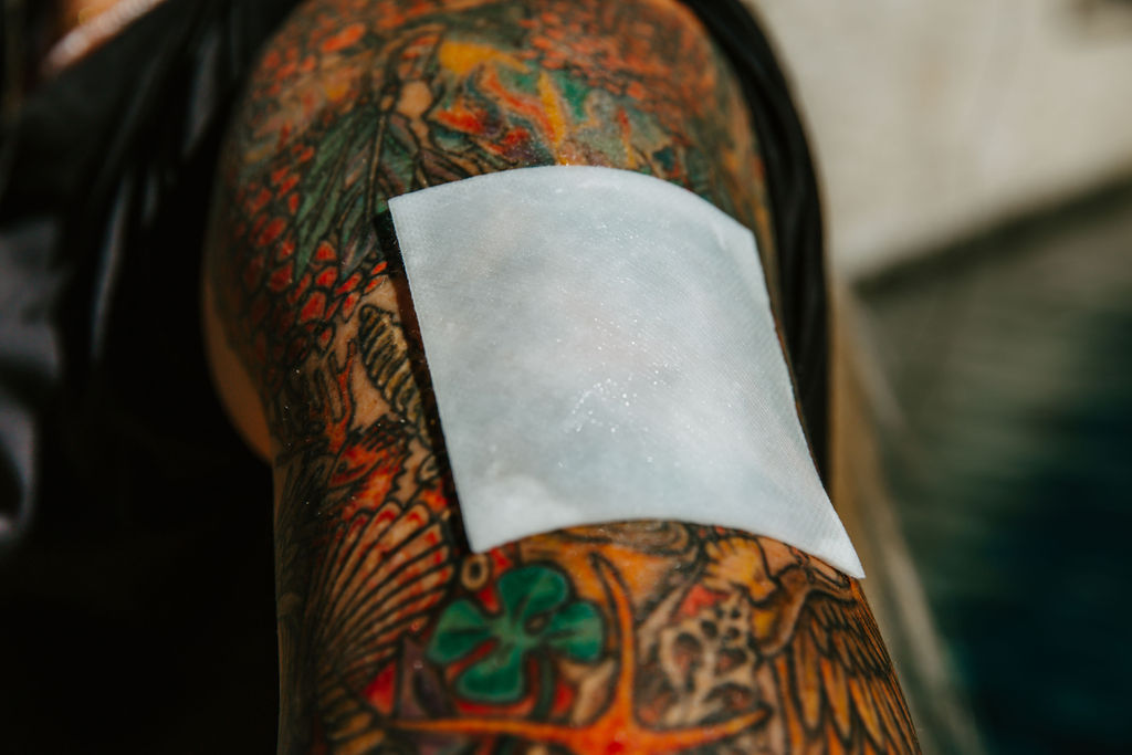 Circure gauze dressing resting on a colorful tattooed arm